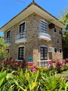 una casa de ladrillo con 2 balcones y flores delante de ella en Pousada Casa da Praia Búzios, en Búzios