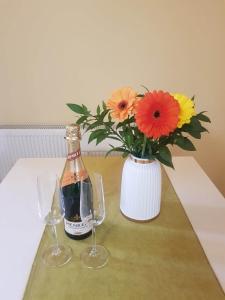 eine Flasche Wein und zwei Gläser auf dem Tisch mit Blumen in der Unterkunft Apartman Fine Rest Brcko in Brčko