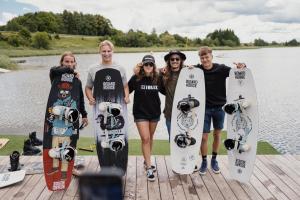 a group of people holding their skateboards on a dock at Wakepond atostogų slėnis in Anykščiai