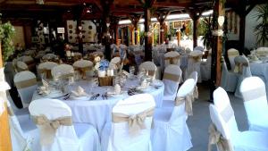 una stanza piena di tavoli e sedie con tovaglie bianche di Tassi Halászcsárda-Harcsa ház a Tass