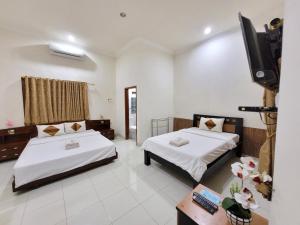 a hotel room with two beds and a television at Ndalem Katong Guest House Ponorogo in Ponorogo