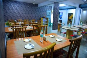 a dining room with a wooden table and chairs at Hotel Housefinch Residency in Bangalore