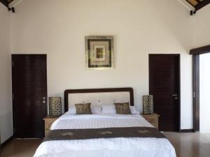 a bedroom with a large bed with white sheets at Taman Dewi Sri Villa et Bungalow in Pemuteran