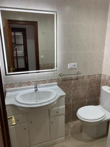 een badkamer met een wastafel, een toilet en een spiegel bij SANTA MARTA PLAYA BAIONA in Baiona