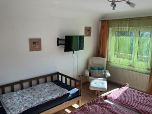 a bedroom with a bed and a chair and a television at TOM’s Appartment in Gröbming