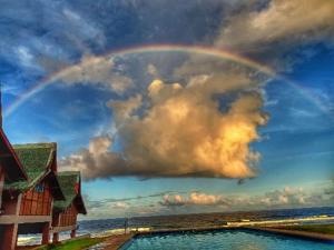 un arco iris en el cielo sobre una piscina en Calicoan Villa, en Sarog
