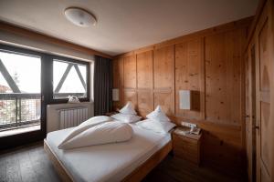 una camera da letto con un letto con cuscini bianchi e una finestra di Green Luxury Hotel Pfösl a Nova Ponente Altre 37 foto