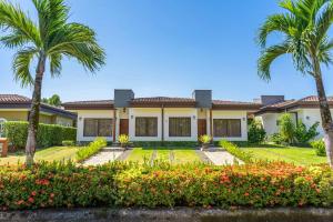 a house with palm trees and flowers in front of it at Costa del Sol 66 in Esterillos