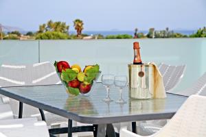 a table with a bowl of fruit and a bottle of wine at Xenos Villa 7 with a Private pool near the sea in Tigaki