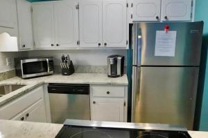 a kitchen with white cabinets and a stainless steel refrigerator at Lazy Palm Heart Of Destin Spring Break Family Beach Vacation! in Destin