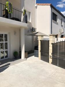 Biały dom z czarnym płotem i patio w obiekcie Villa Stef w mieście Lunel-Viel