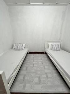 two beds in a room with white walls at lily maison in Tanah Rata