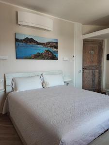 Un dormitorio con una cama blanca y una pintura en la pared en Antica Isola, en Olbia