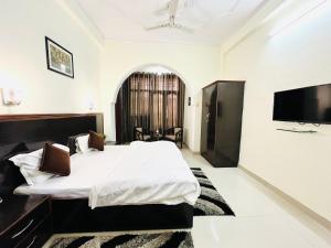 a bedroom with a bed and a flat screen tv at Alibaba’s Indiana Homestay in Tājganj