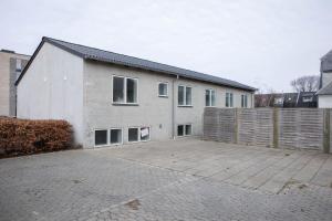 a white house with a fence in front of it at Grindsted - Billund Holiday Rooms in Grindsted