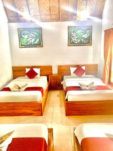 a bedroom with two beds with red pillows at Jona Bungalow in Nusa Penida