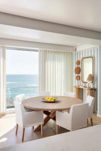 uma sala de jantar com uma mesa e cadeiras com vista para o oceano em The Nici Clifton Sea View Apartments em Cidade do Cabo