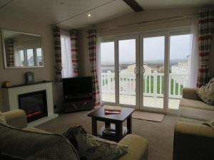 a living room with a fireplace and a view of a balcony at alphi3 in Bude
