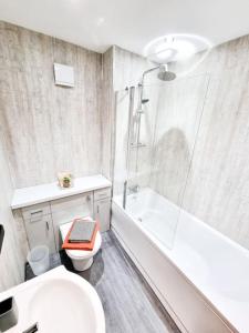 uma casa de banho com um chuveiro, um WC e um lavatório. em Stunning Flat Close to Beach em Swansea