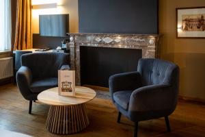 two chairs and a table in front of a fireplace at La Villa des Fleurs in Spa