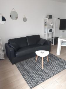 sala de estar con sofá negro y mesa en Maison de pêcheur idéalement située. en Le Tréport