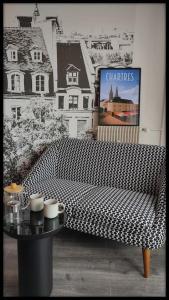 a living room with a checkered couch and a table at Le p'tit Beauce au Cœur de Chartres in Chartres