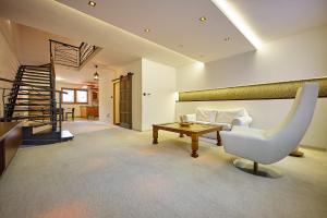 a living room with a white chair and a table at HOTEL Garni PATRIOT in Trnava
