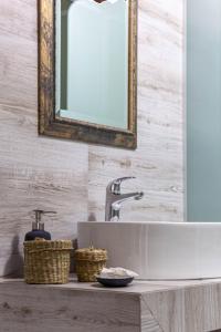 a bathroom sink with a mirror and baskets on a counter at Althaia Pension in Nafplio