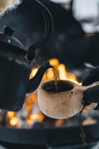 uma pessoa está segurando uma xícara de café em um fogão em Venejoen Piilo - Naava em Romppala