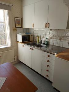 uma cozinha com armários brancos, um lavatório e um micro-ondas em Mariannelund cottage em Mariannelund