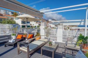 a patio with benches and tables and an umbrella at The Moonlight Sea View by Hello Homes Sitges in Sitges