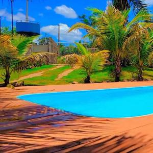 a blue swimming pool on a beach with palm trees at Chácara São Francisco in Olímpia