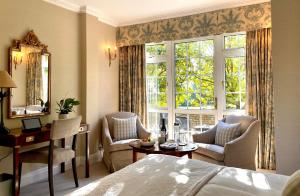 a bedroom with a bed and a desk and a window at Longueville Manor in Saint Helier Jersey