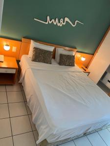 1 dormitorio con 1 cama blanca grande y 2 almohadas en Praia do Canto Apart Hotel Frente Mar en Vitória