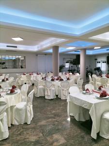 un salón de banquetes con mesas blancas y sillas blancas en Hotel Ala Bianca, en Ameglia