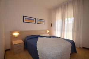 a bedroom with a blue bed and a window at Villaggio Dei Gelsomini in Bibione