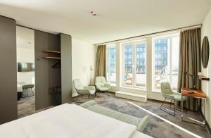 1 dormitorio con 1 cama, escritorio y ventanas en Motel One Essen, en Essen