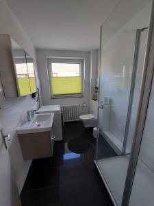 een badkamer met een wastafel, een douche en een toilet bij Fewo am Kurpark mit Balkon in Wilhelmshaven