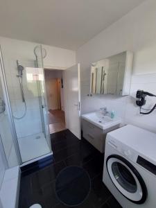 een badkamer met een douche en een wasmachine bij Fewo am Kurpark mit Balkon in Wilhelmshaven