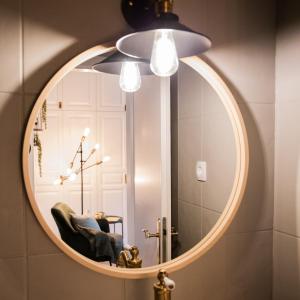 a mirror in a bathroom with a chair and a lamp at Privatzimmer - Sieben an der Donau in Ottensheim
