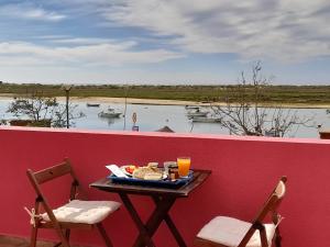 uma mesa com um prato de comida e duas cadeiras em Casa Viana - Guesthouse em Cabanas de Tavira