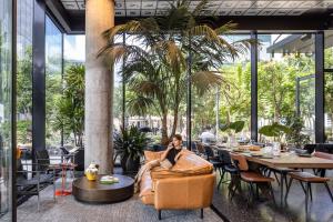 a woman sitting in a chair in a restaurant at Play Midtown Hotel Tel Aviv in Tel Aviv