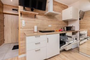 a kitchen with white cabinets and a wooden wall at Cozy studio in Downtown Gdańsk by Renters in Gdańsk