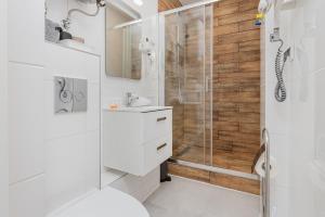 a white bathroom with a shower and a sink at Cozy studio in Downtown Gdańsk by Renters in Gdańsk