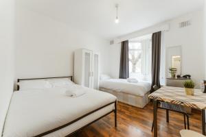 - une chambre avec 2 lits et une table dans l'établissement Upton Park Bedrooms 25 min to Central London, à Londres