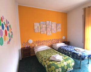 ローマにあるMy Vatican Houseのオレンジ色の壁の客室内のベッド2台