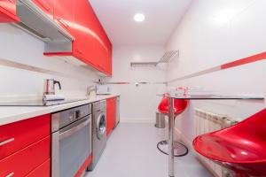 a kitchen with red cabinets and a red stool at Deslumbrante Apto Barrio de Las Letras by Batuecas in Madrid +26 photos