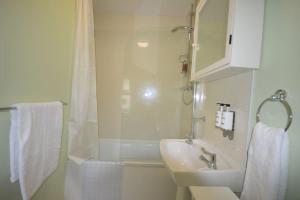 La salle de bains blanche est pourvue d'un lavabo et d'une douche. dans l'établissement Mountain Escape - Cosy 2 bed house in Afan Valley, à Port Talbot