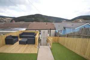 a backyard with a wooden fence and a wooden deck at Mountain Escape - Cosy 2 bed house in Afan Valley in Port Talbot