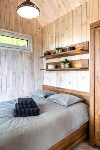 1 dormitorio con 1 cama en una pared de madera en Szczurze wzgórze, en Zachełmie